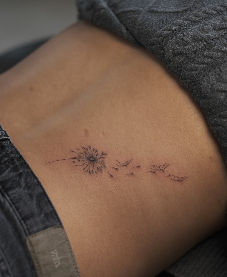 Fijne tattoo van een uitgebloeide paardenbloem op de heup