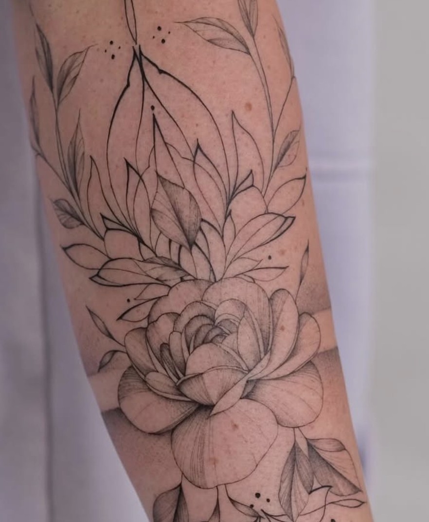Fineline bloementattoo langs de bovenarm