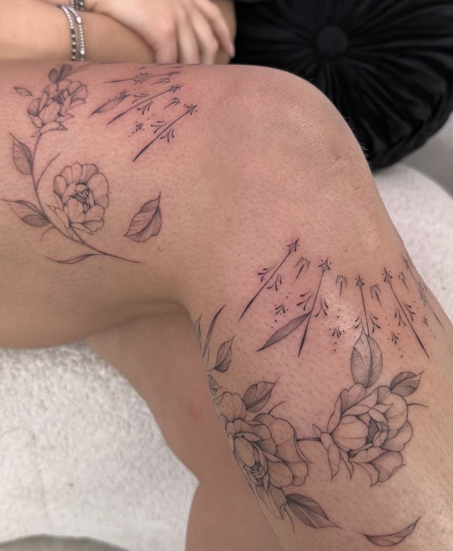 Fineline bloementattoo over de knie en het bovenbeen