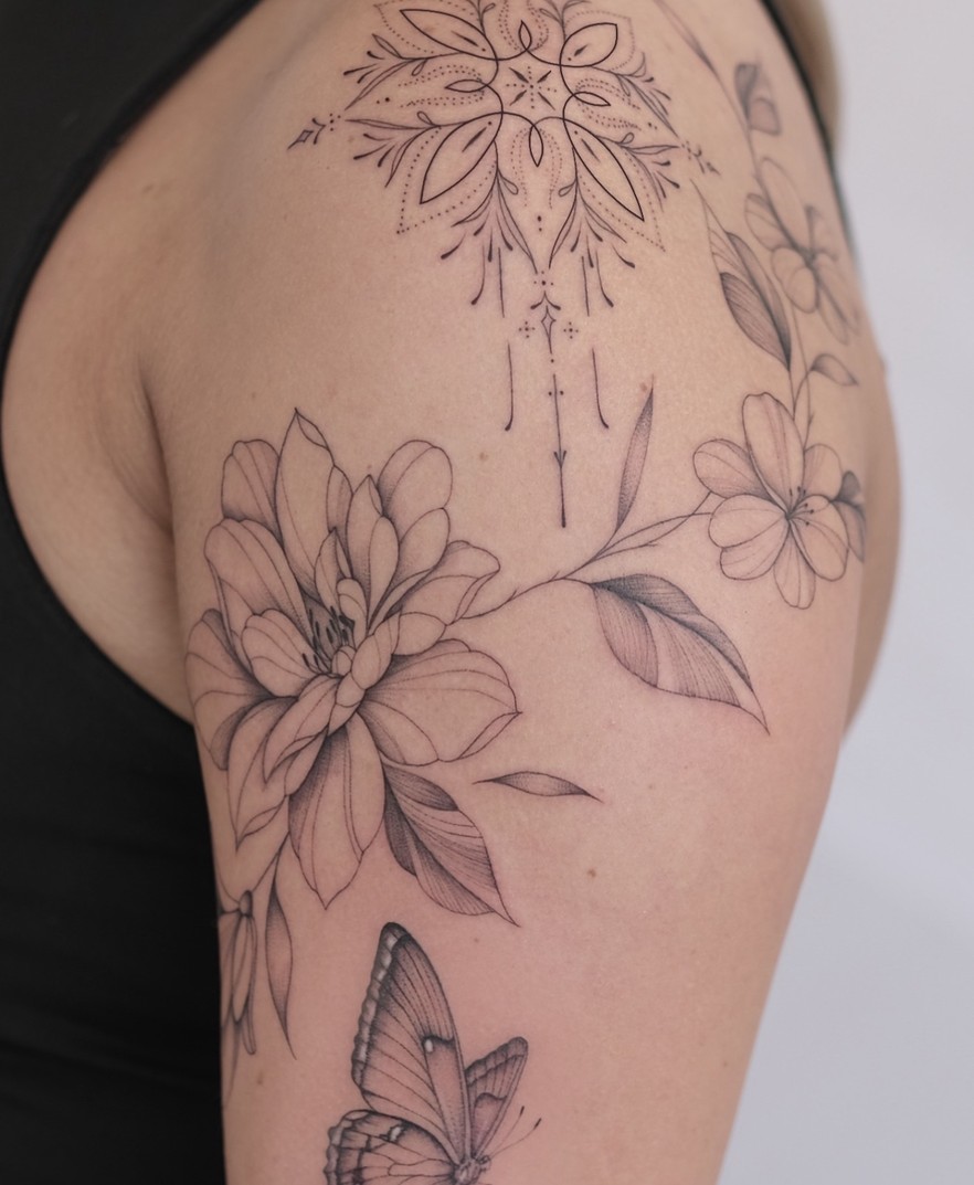 Fineline tattoo met bloemen en een mandala over de schouder