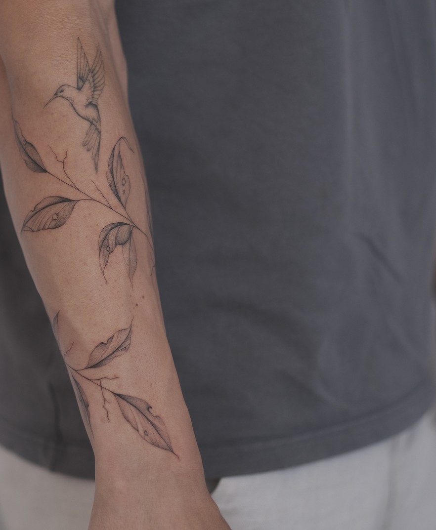 Fineline tattoo van een lange bloementak over de hele arm