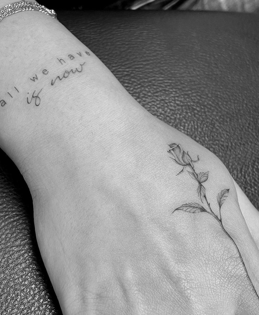 Fineline tattoo van een roosje en fijne tekst op de hand