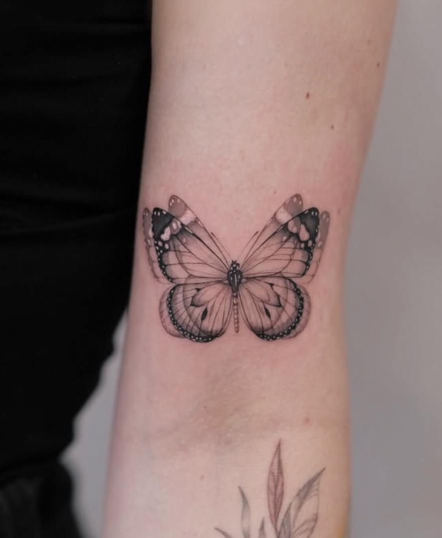 Fineline tattoo van een vlinder net boven de pols