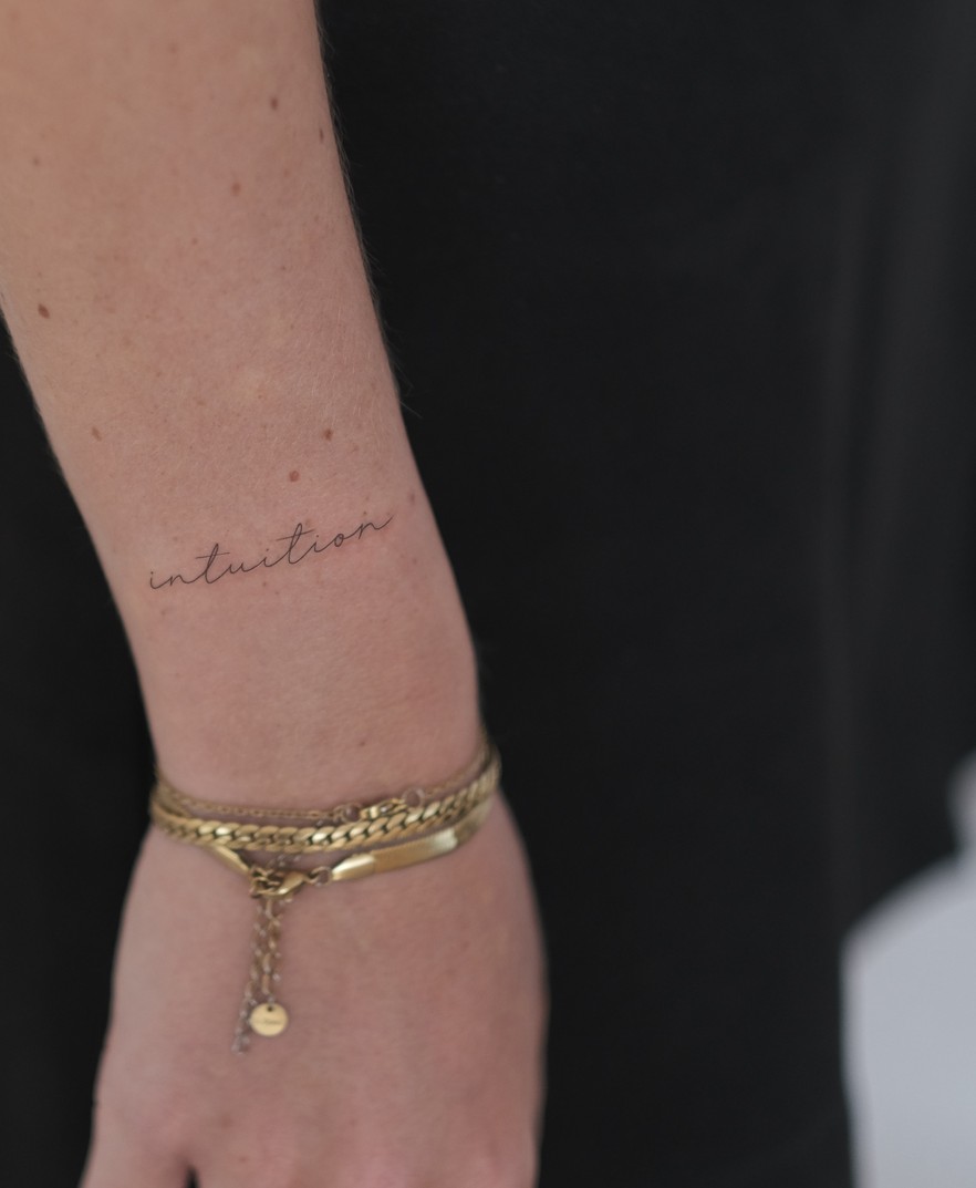 Kleine fineline tattoo met fijn geschreven tekst op de pols