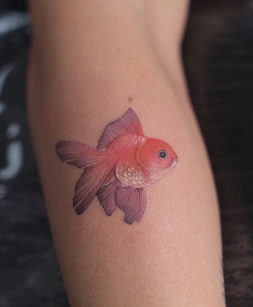 Tattoo van een goudvis in kleur op de arm